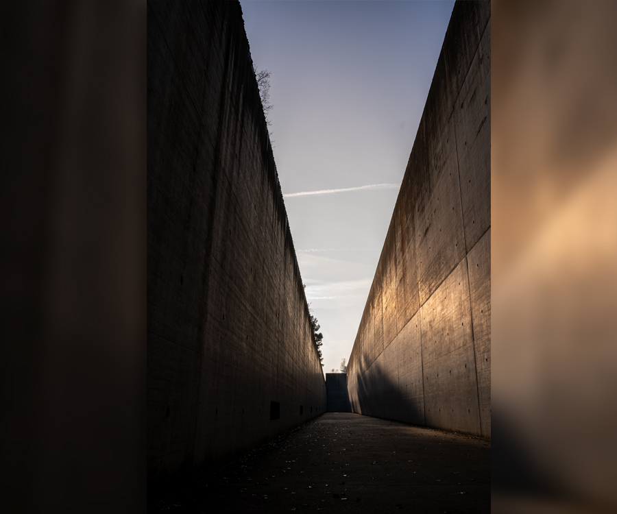 Hohe Betonwände der Gedenkstätte Bergen-Belsen mit Blick in den Himmel