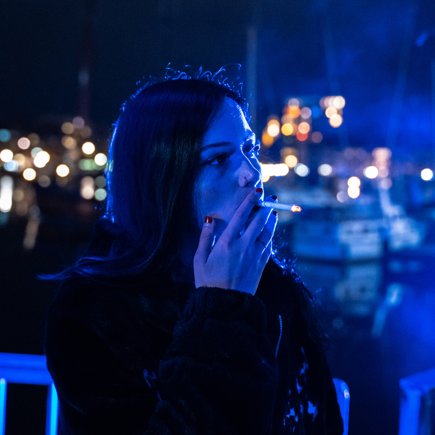 Karina Rose im blauen Licht, Zigarette im Mund, Blick in die Ferne