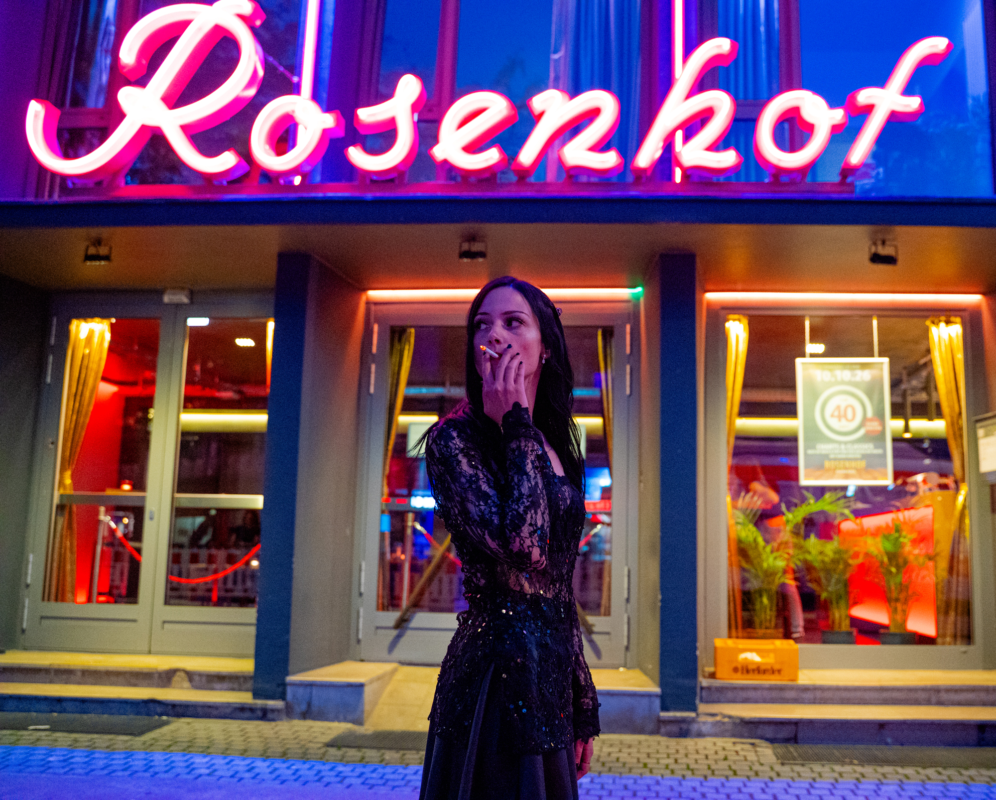 Karina Porträt mit Zigarette im Mund vor dem Rosenhof Neon Schriftzug