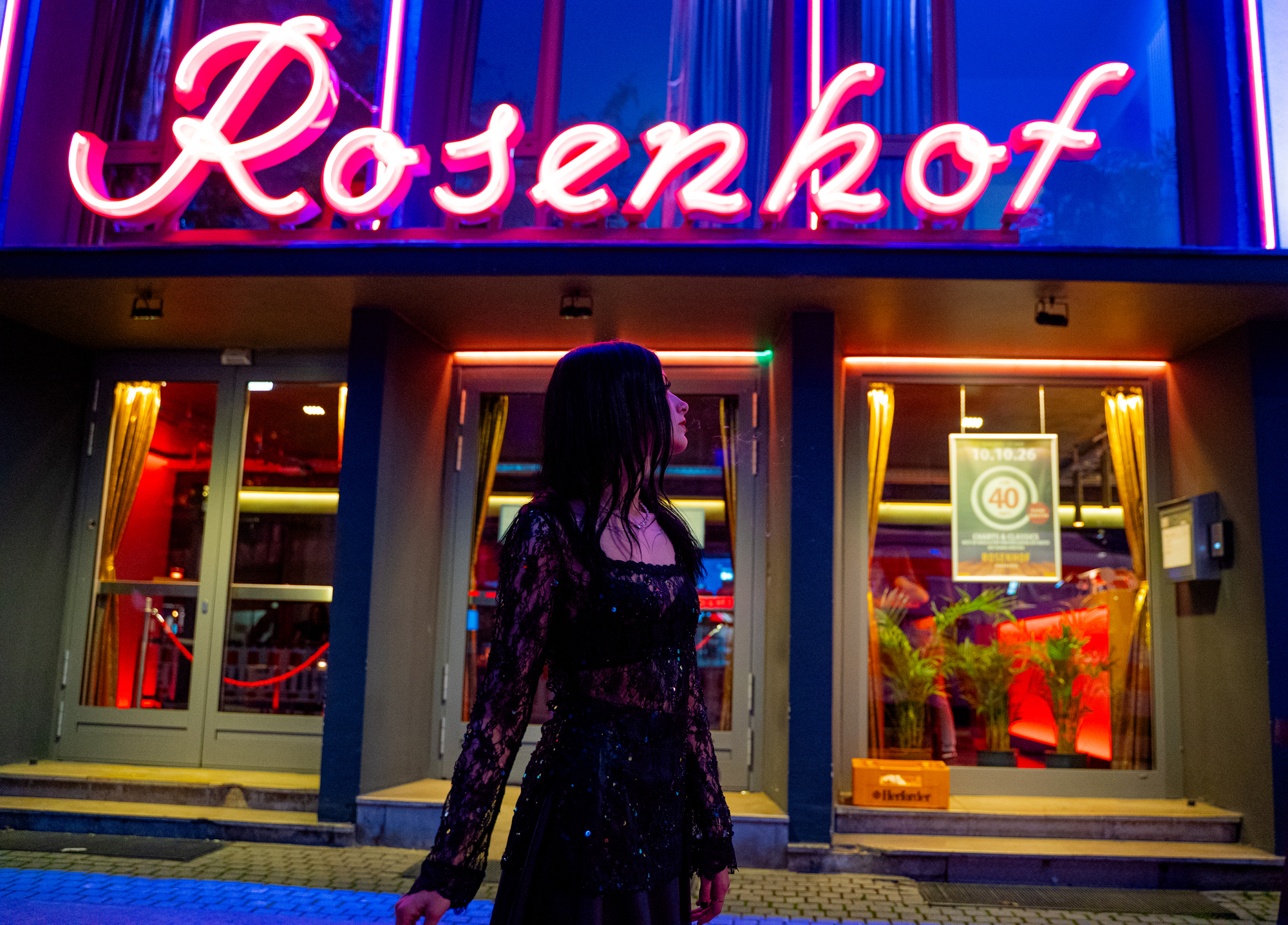 Karina Porträt vor dem leuchtenden Rosenhof Neon Schriftzug