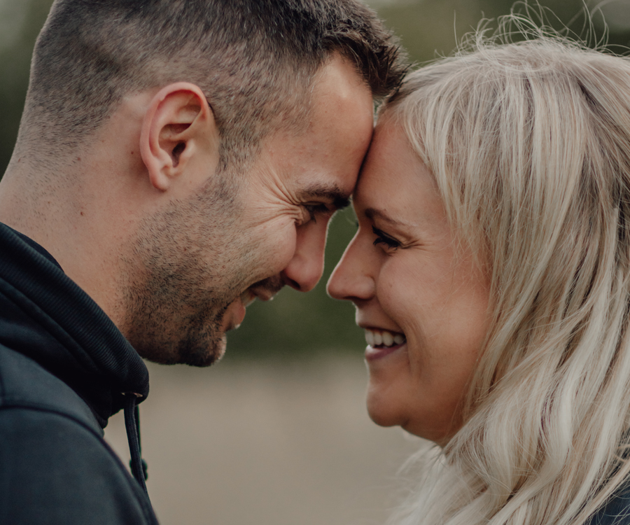 Verliebtes Paar steht Stirn an Stirn und lächelt zärtlich