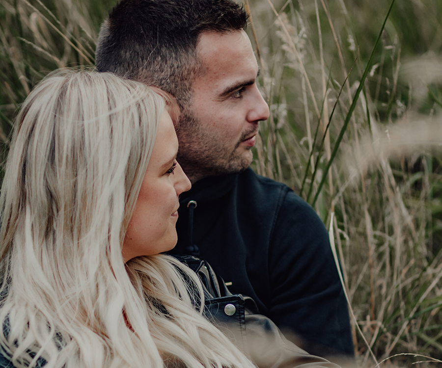 Verliebtes Paar liegt Arm in Arm in einem Feld mit Pflanzen