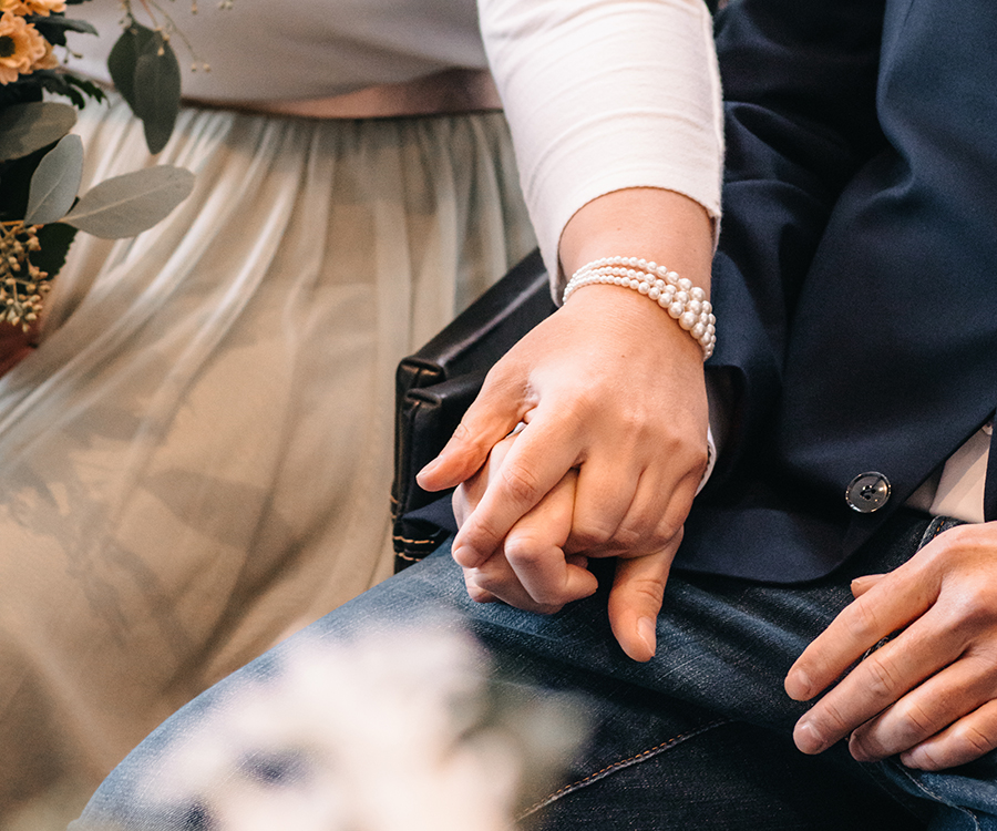 Hände eines Brautpaares während der Trauung, sie halten sich fest